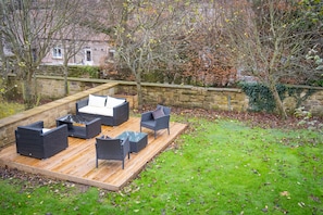 An outdoor patio with wicker furniture and a wooden deck.