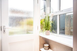 A room with a window, a potted plant, and a decorative bowl on a shelf.