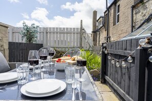 A dining table set outdoors with plates, glasses, and cutlery.