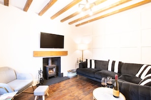 A living room with a fireplace, a sofa, a television, and a wine bottle.