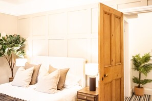 A hotel room with a bed, bedside tables, a nightstand, a lamp, and a potted plant. - Northern Hideaways, St Cuthberts (Seahouses)
