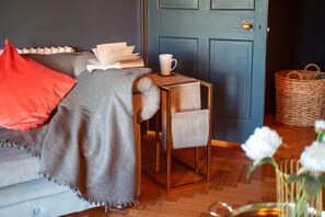 Une pièce confortable avec un canapé, une petite table sur laquelle se trouve une tasse, un panier et une porte.