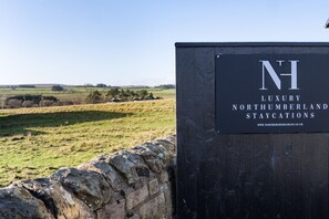 A sign for luxury Northumberland staycations with a view of a rural landscape. - Northern Hideaways, Otterburn (Otterburn)