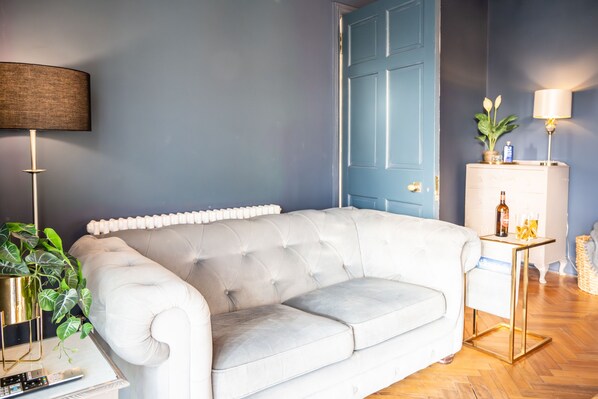 A living room with a white sofa, a lamp, a radiator, and a door. - Northern Hideaways, Otterburn (Otterburn)