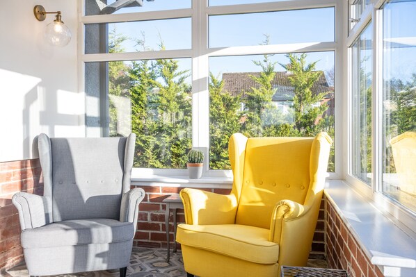 A room with a large window, two armchairs, a small table, and a potted plant. - Northern Hideaways, Otterburn (Otterburn)