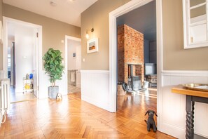 A spacious living room with hardwood flooring, a large potted plant, and a fireplace.