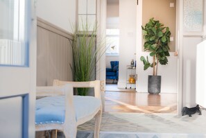 Une pièce avec une chaise en bois, une plante en pot et un chat sur le sol.