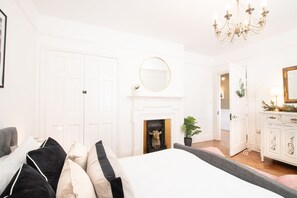 A bedroom with a large bed, a fireplace, a mirror, and a chandelier. - Northern Hideaways, Otterburn (Otterburn)