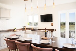 A modern kitchen with a large island, pendant lighting, and a view of the countryside. - Northern Hideaways, Otterburn (Otterburn)