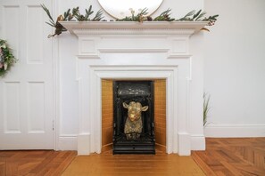 Une cheminée ornée d’une tête de vache décorative, des murs blancs et un plancher en bois.