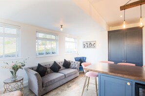 A modern kitchen with a grey sofa, a wooden dining table, and a blue cabinet. - Northern Hideaways, Otterburn (Otterburn)