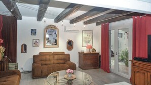 A living room with a brown sofa, a glass coffee table with flowers, a wooden cabinet, and a large mirror on the wall. - Pet friendly home in St Julien de Peyrolas (St Julien de Peyrolas)