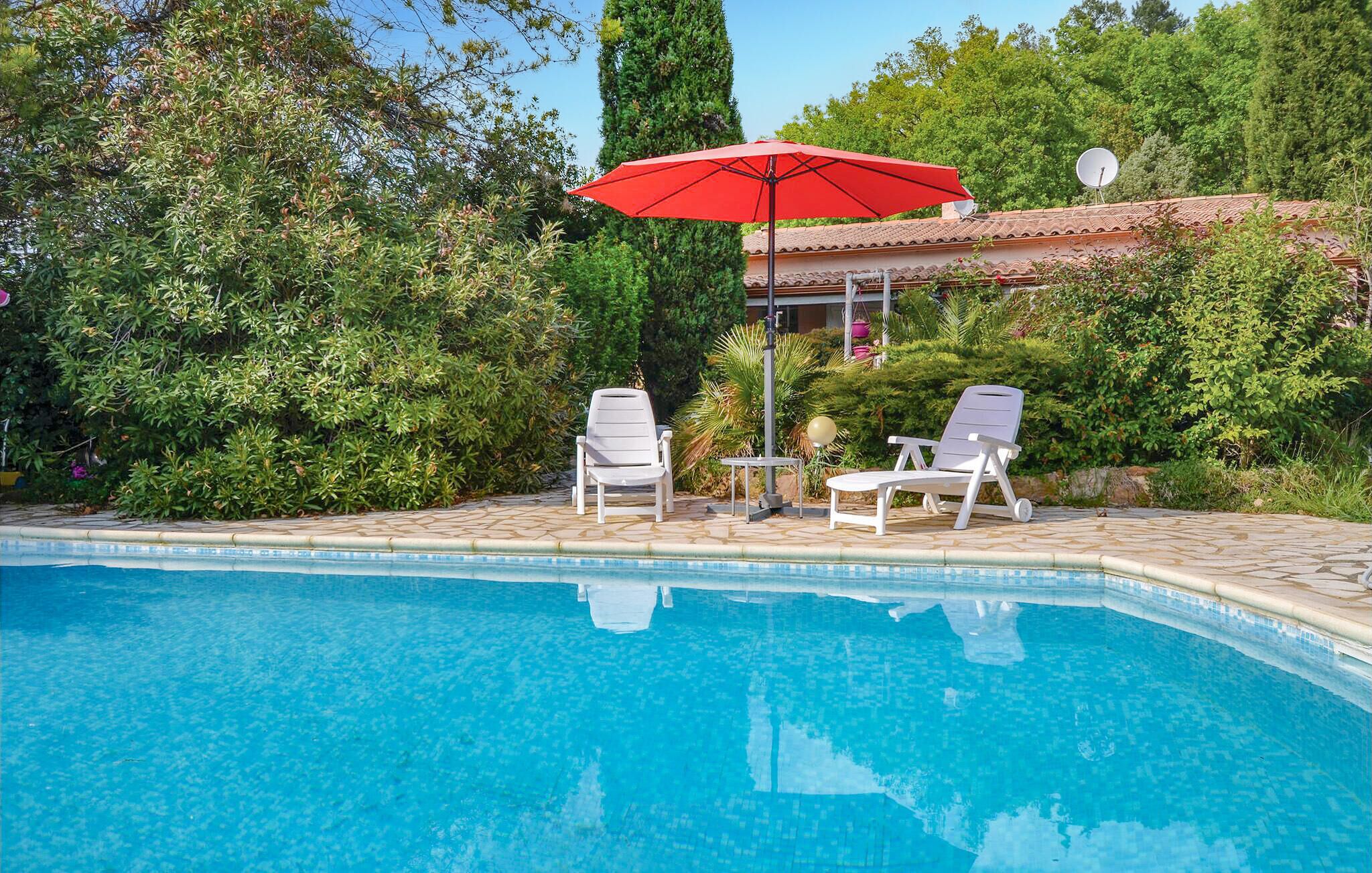 A swimming pool with two white lounge chairs and a red umbrella.