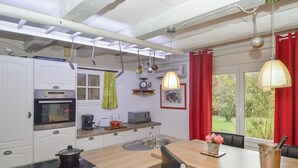 A modern kitchen with white cabinets, a built-in oven, a sink, and a dining area with a table and chairs. - Pet friendly home in St Julien de Peyrolas (St Julien de Peyrolas)