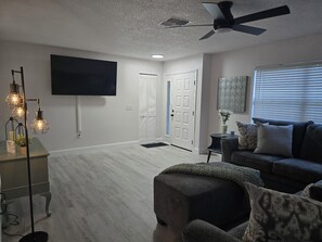 Relax in this stylish living room with a flat-screen TV, comfortable sofa, and ottoman.