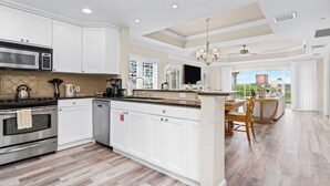 Cocina amplia con armarios blancos, una isla grande y vistas al exterior.