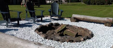 A fire pit area with logs and seating, surrounded by white gravel.
