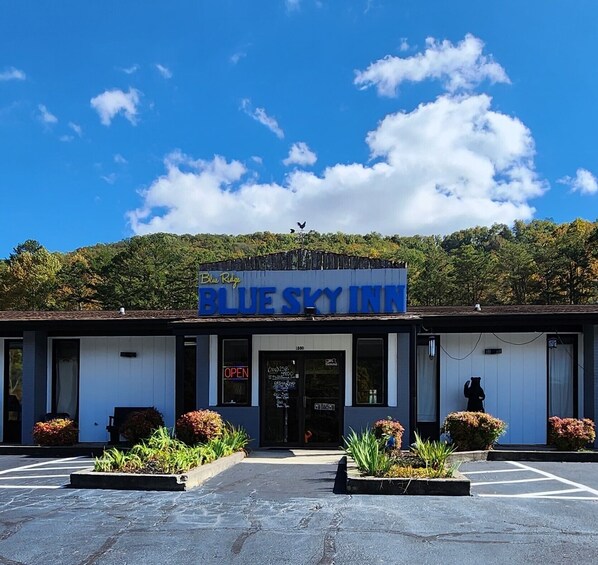A Blue Sky Inn with a signboard, a parking lot, and a forested hill in the background. - Blue Sky Inn (Blue Ridge)
