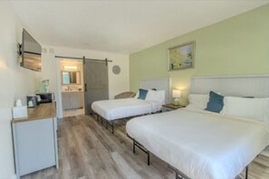 A hotel room with a large bed, two smaller beds, a desk, and a bathroom visible through an open door. - Blue Sky Inn (Blue Ridge)