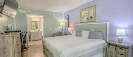 A bedroom with a bed, a dresser, a nightstand, a lamp, and a painting on the wall.