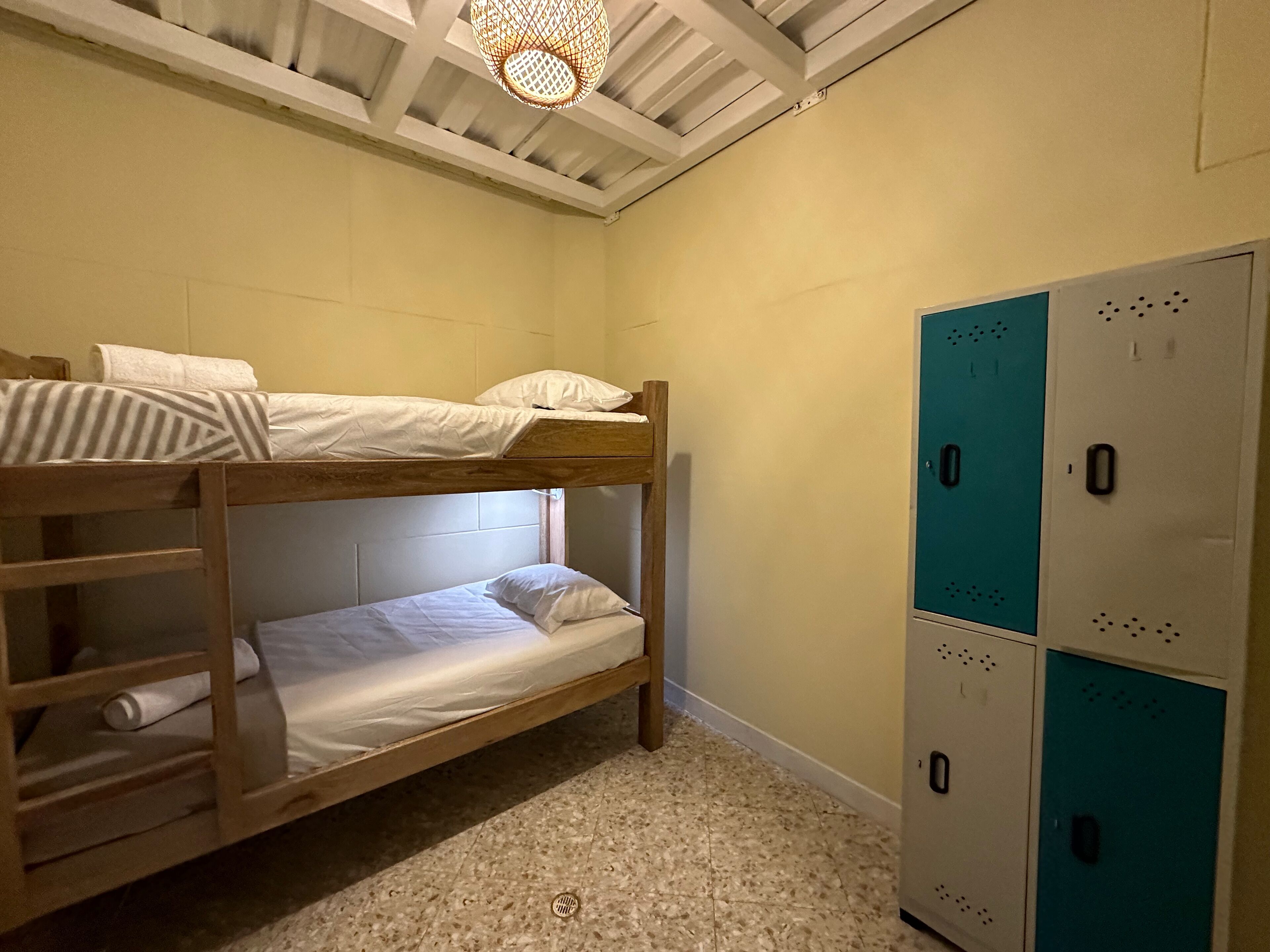 Habitación con literas, ventilador de techo, armario con varios compartimentos y piso de baldosas.