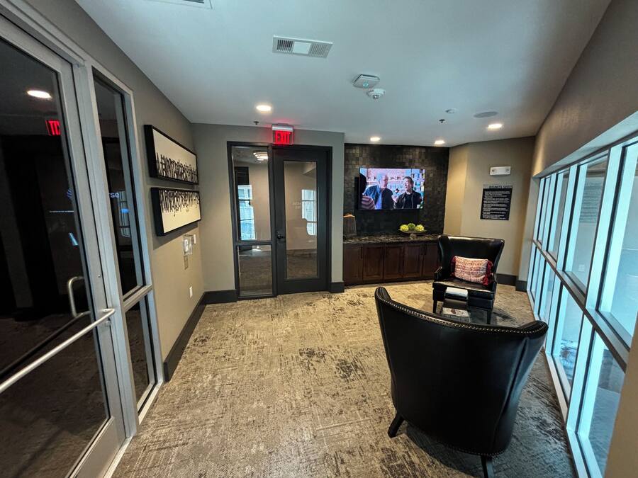 A lobby with a reception desk, a television mounted on the wall, and a seating area with a chair.