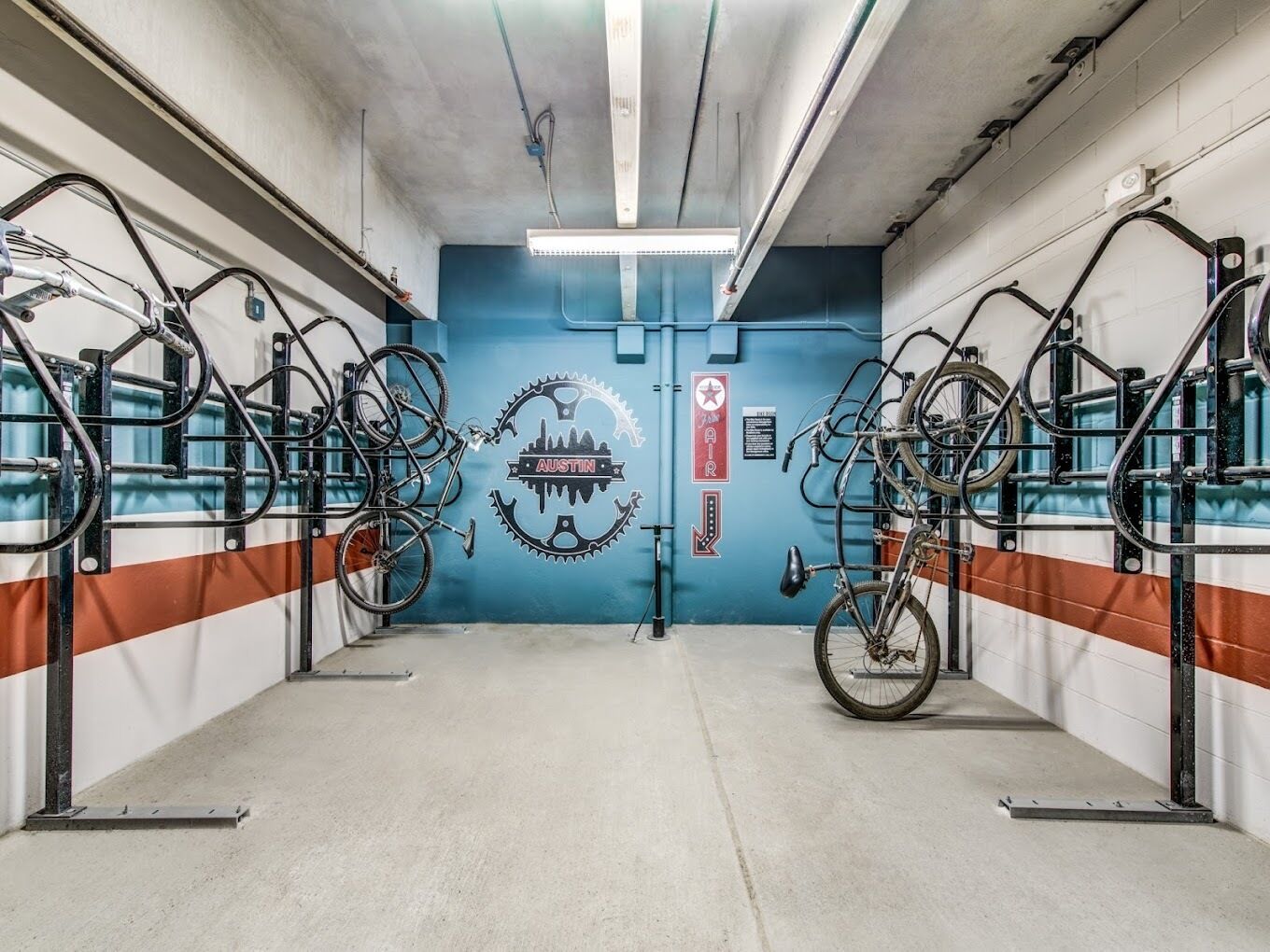 A bike rental station with multiple bicycles and a wall-mounted logo.