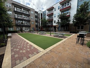 A courtyard with a green lawn, picnic tables, and benches.