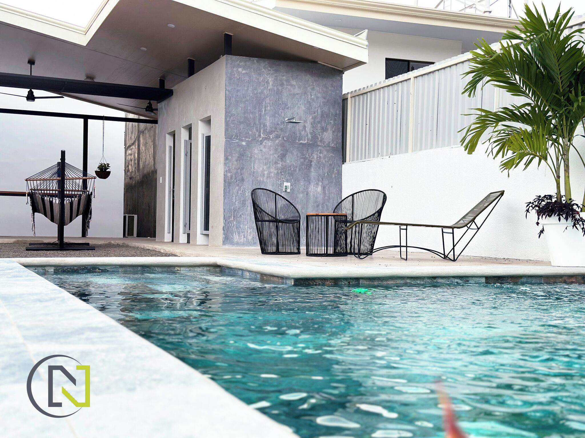 A modern outdoor pool area with a seating arrangement and a pergola.