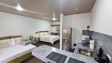 Ein kompaktes Hotelzimmer mit Bett, einer Sitzecke, einer Küchenzeile und einer kleinen Essecke.