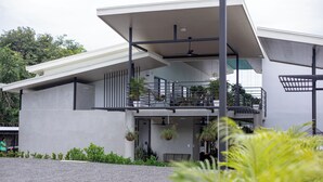 A modern building with a flat roof, large windows, and a balcony with hanging planters. - Nomad Living CR (Tárcoles)