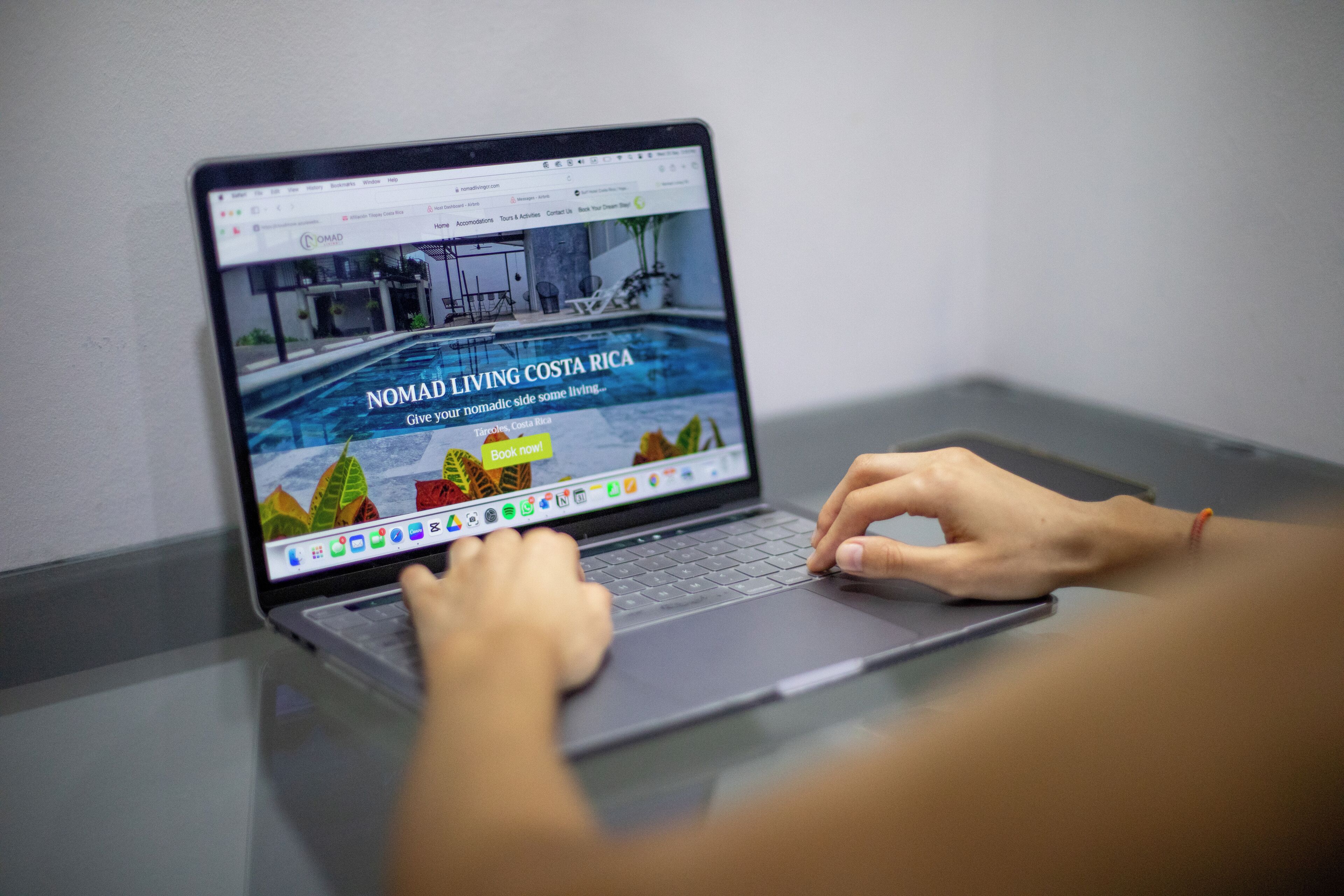 Un ordinateur portable affichant une page Web dont le titre est « Nomad Living Costa Rica » et qui comporte un bouton « Réserver maintenant ».