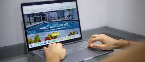 Un ordinateur portable affichant une page Web dont le titre est « Nomad Living Costa Rica » et qui comporte un bouton « Réserver maintenant ».