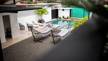A modern outdoor pool area with lounge chairs and a small table.