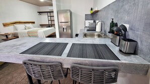Una cocina moderna con una isla grande, electrodomésticos de acero inoxidable y una zona de bar con sillas de mimbre.