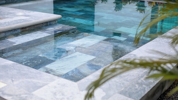 Una piscina con un diseño geométrico de azulejos y un borde de piedra.
