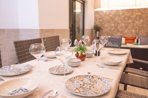 A dining table set with plates, wine glasses, and cutlery, surrounded by wicker chairs. - Casa Flor del Rocío: Style, Comfort & Wi-Fi Near Seville (La Rinconada)