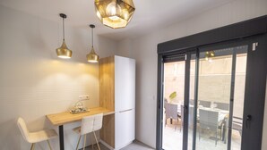 A modern kitchen with a wooden countertop, two pendant lights, and a sliding glass door leading to an outdoor patio. - Casa Flor del Rocío – Seville – 4 Bedrooms for 8 – AC Throughout – Terrace & Parking (La Rinconada)