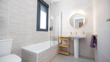 A modern bathroom with a bathtub, toilet, and sink.