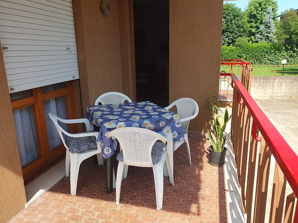 A patio with a table and chairs, a potted plant, and a red railing.
