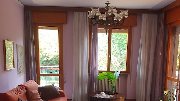 Un salon comprenant un canapé, une table basse, un lustre et donnant sur un espace verdoyant.