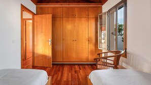 A bedroom with wooden flooring, a bed, a chair, and a wardrobe. - Vacation Home 'Casa Tagoro, Facing The Ocean' with Sea View, Private Terrace and Wi-Fi (Tacoronte)