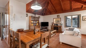 A spacious living area with a wooden dining table, a sofa, a television, and a bookshelf. - Vacation Home 'Casa Tagoro, Facing The Ocean' with Sea View, Private Terrace and Wi-Fi (Tacoronte)