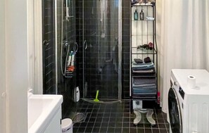 A compact bathroom with a shower, toilet, and a small shelf with toiletries. - Cozy home in Heby with WiFi (Heby)