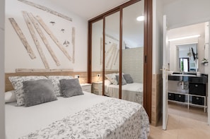 A bedroom with two beds, a wooden headboard, a mirror, a dresser, and a brick wall.