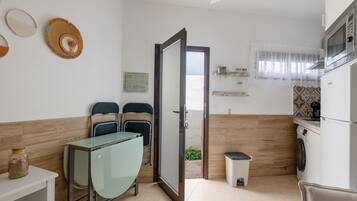 A kitchen with a microwave, a sink, a trash bin, and a door leading outside.