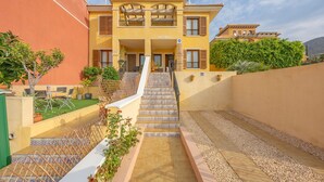 A multi-story hotel with a central staircase, outdoor seating, and a view of the surrounding landscape. - Holiday Home 'Adosado En Finestrat' with Mountain View, Wi-Fi and Air Conditioning (Finestrat)