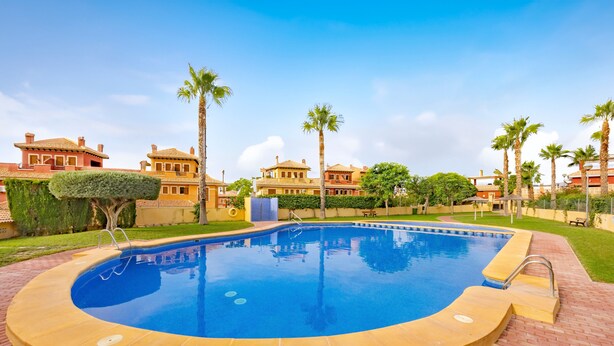 A swimming pool with a brick deck, surrounded by palm trees and houses. - Holiday Home 'Adosado En Finestrat' with Mountain View, Wi-Fi and Air Conditioning (Finestrat)