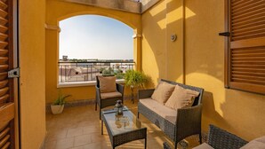 A balcony with a glass table, wicker furniture, a potted plant, and a view of the cityscape. - Holiday Home 'Adosado En Finestrat' with Mountain View, Wi-Fi and Air Conditioning (Finestrat)