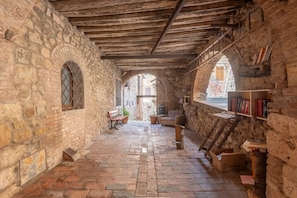 A stone-walled interior with a wooden ceiling, a bench, a sofa, and a bookshelf.